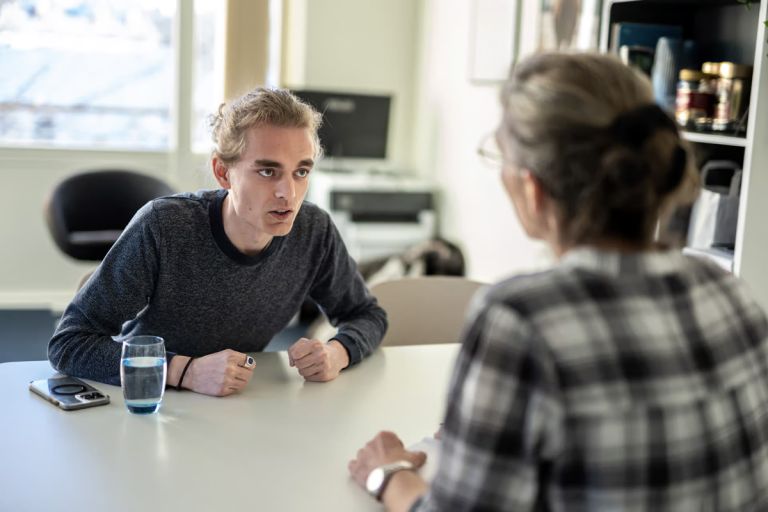 En ung mand og en kvinde taler sammen ved et bord